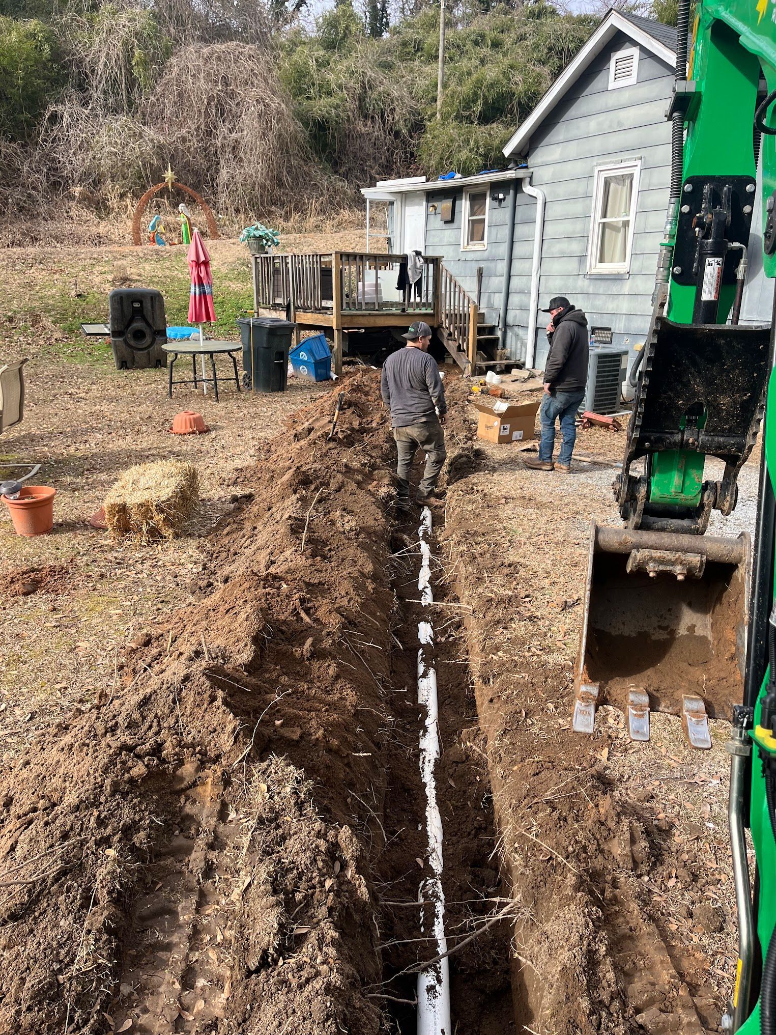 A man is digging a hole in the dirt in front of a house.