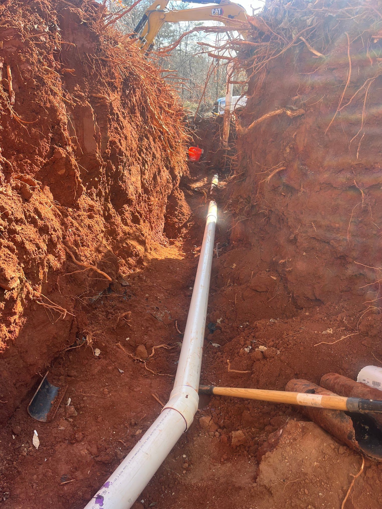 A person is digging a hole with a shovel and a pipe.