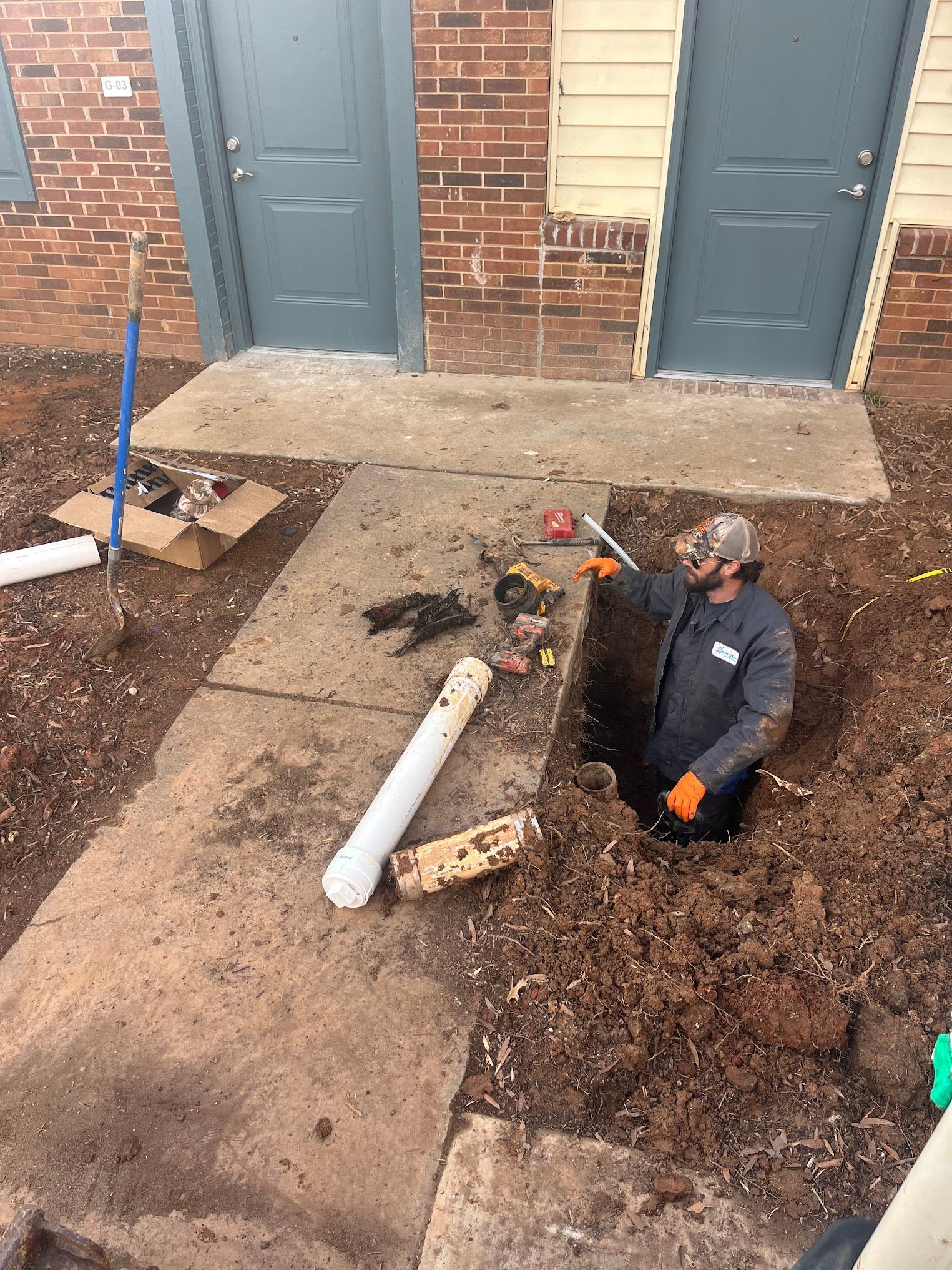 A man is digging a hole in the ground in front of a building.