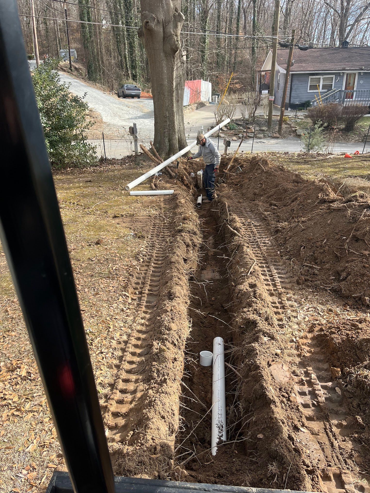 A man is digging a hole in the dirt in a yard.