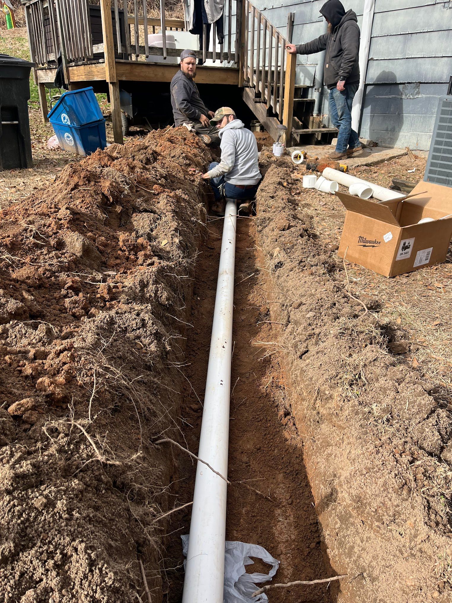 A group of men are working on a pipe in the dirt.