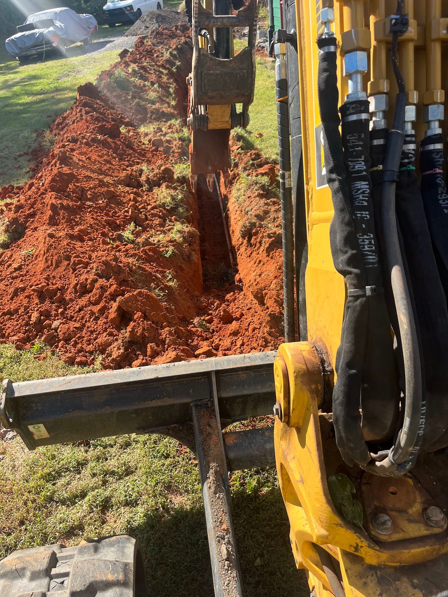 A yellow excavator is digging a trench in the ground.