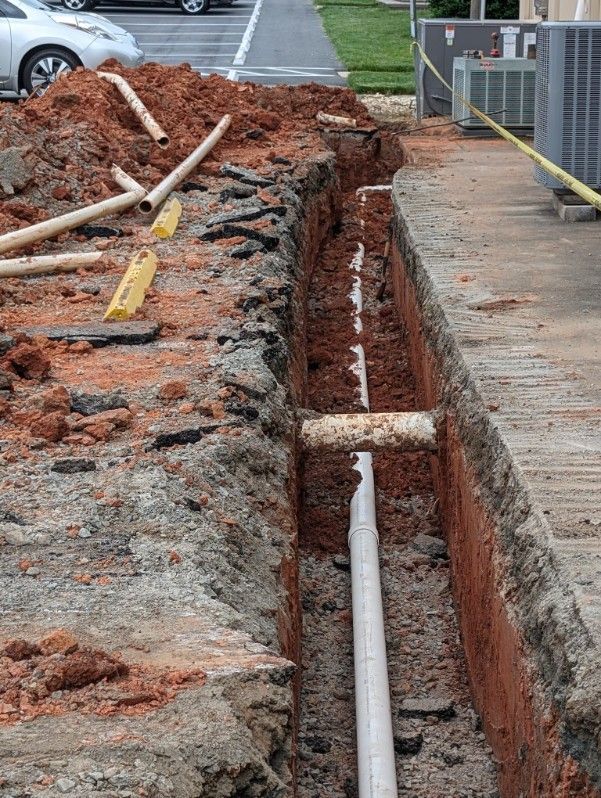 A drain pipe is being installed in a trench.