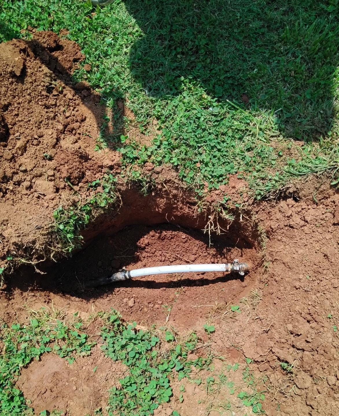 A white pipe is sticking out of a hole in the ground.