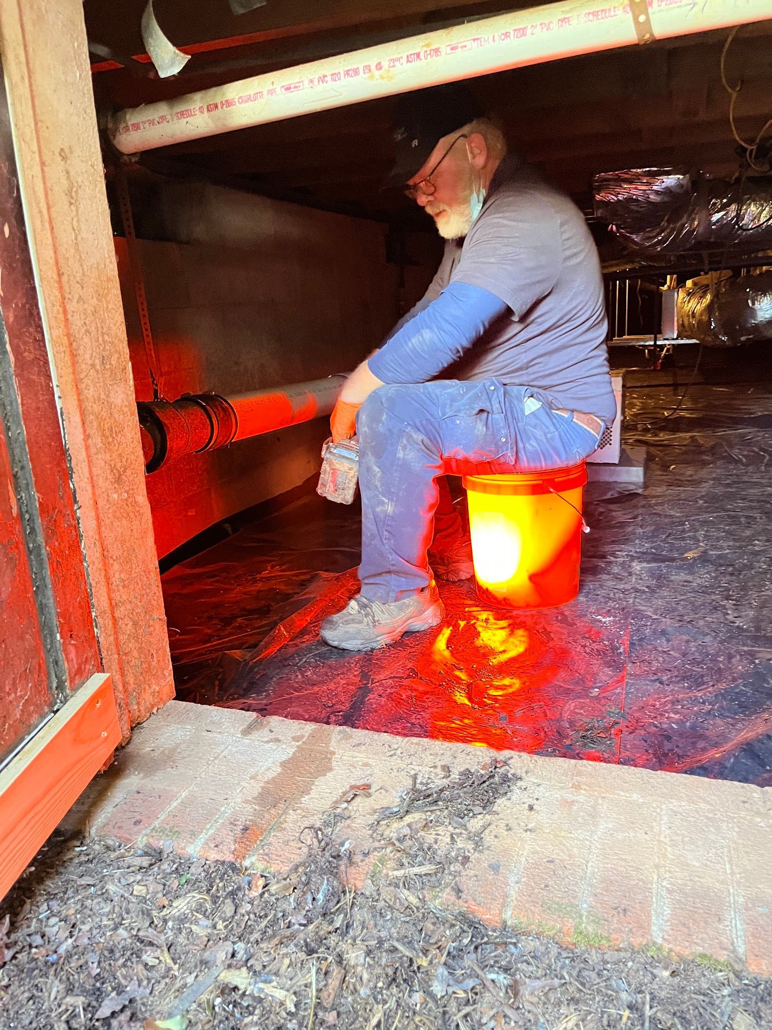 A man is sitting on a bucket in a basement.
