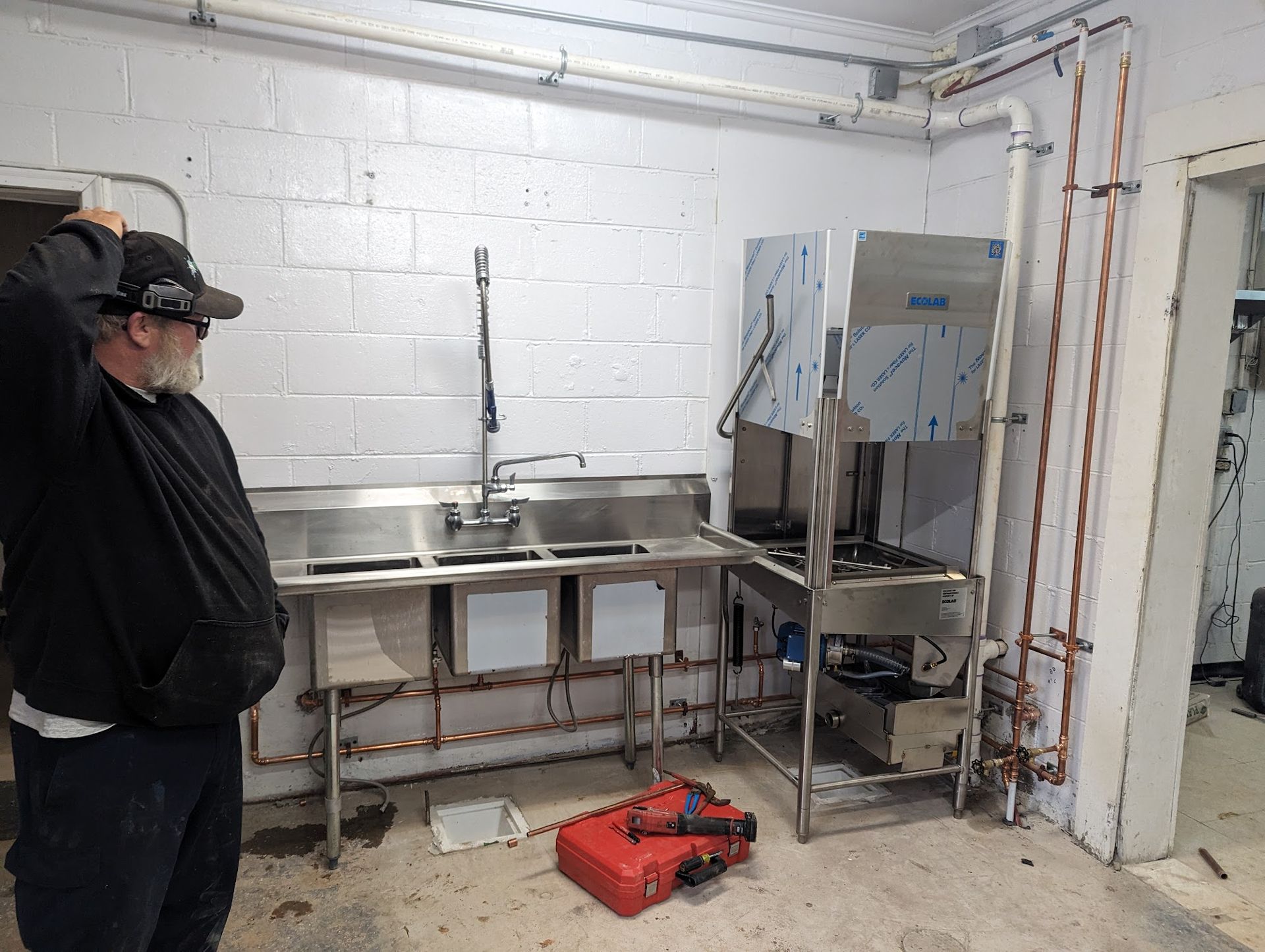 A man is standing in a kitchen with a sink and a dishwasher.