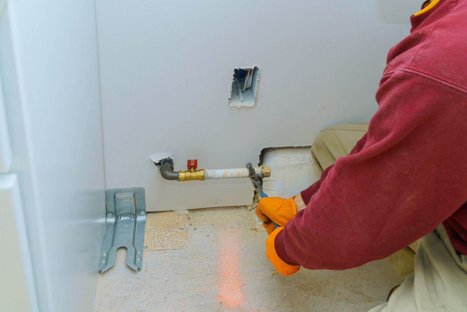A man is working on a pipe in a bathroom.
