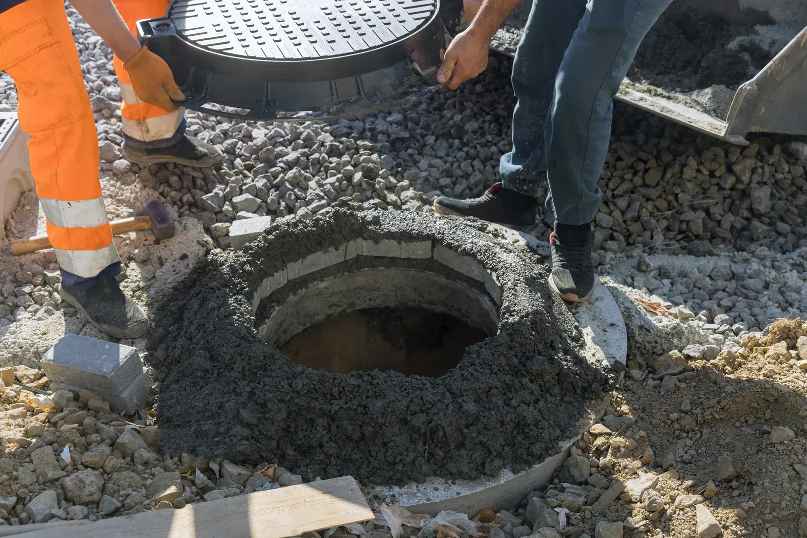 A manhole cover is being installed in a hole in the ground.