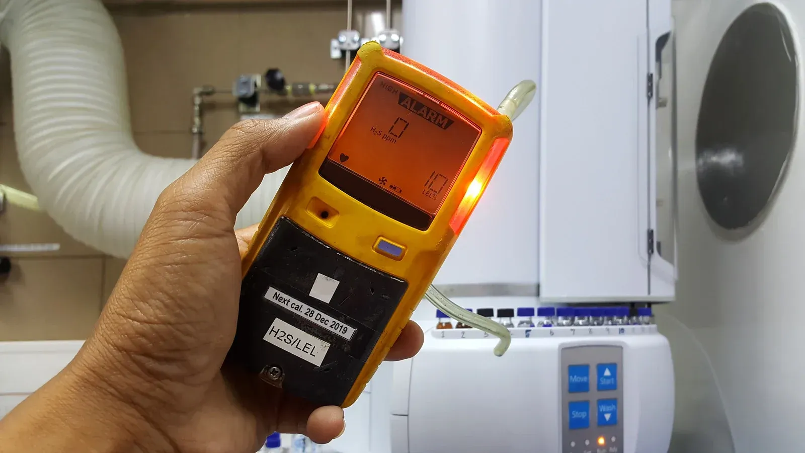 A person is holding a gas detector in their hand.