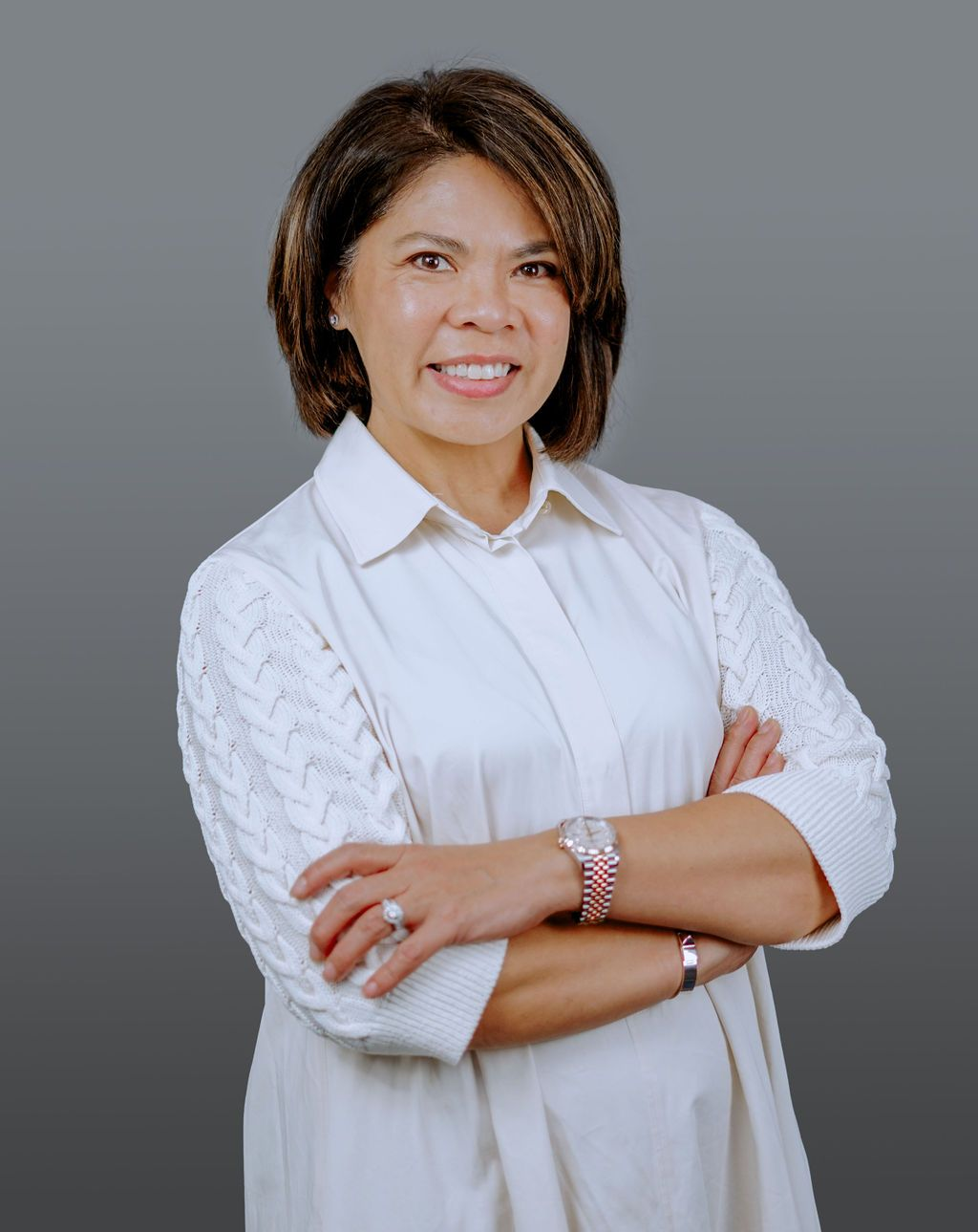 A woman in a black dress and scarf is standing in front of a tree.