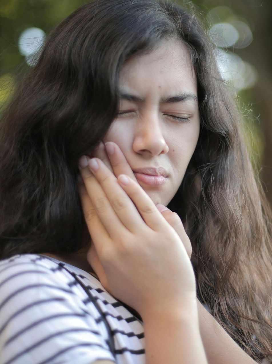 A woman is holding her face in pain because of a toothache.