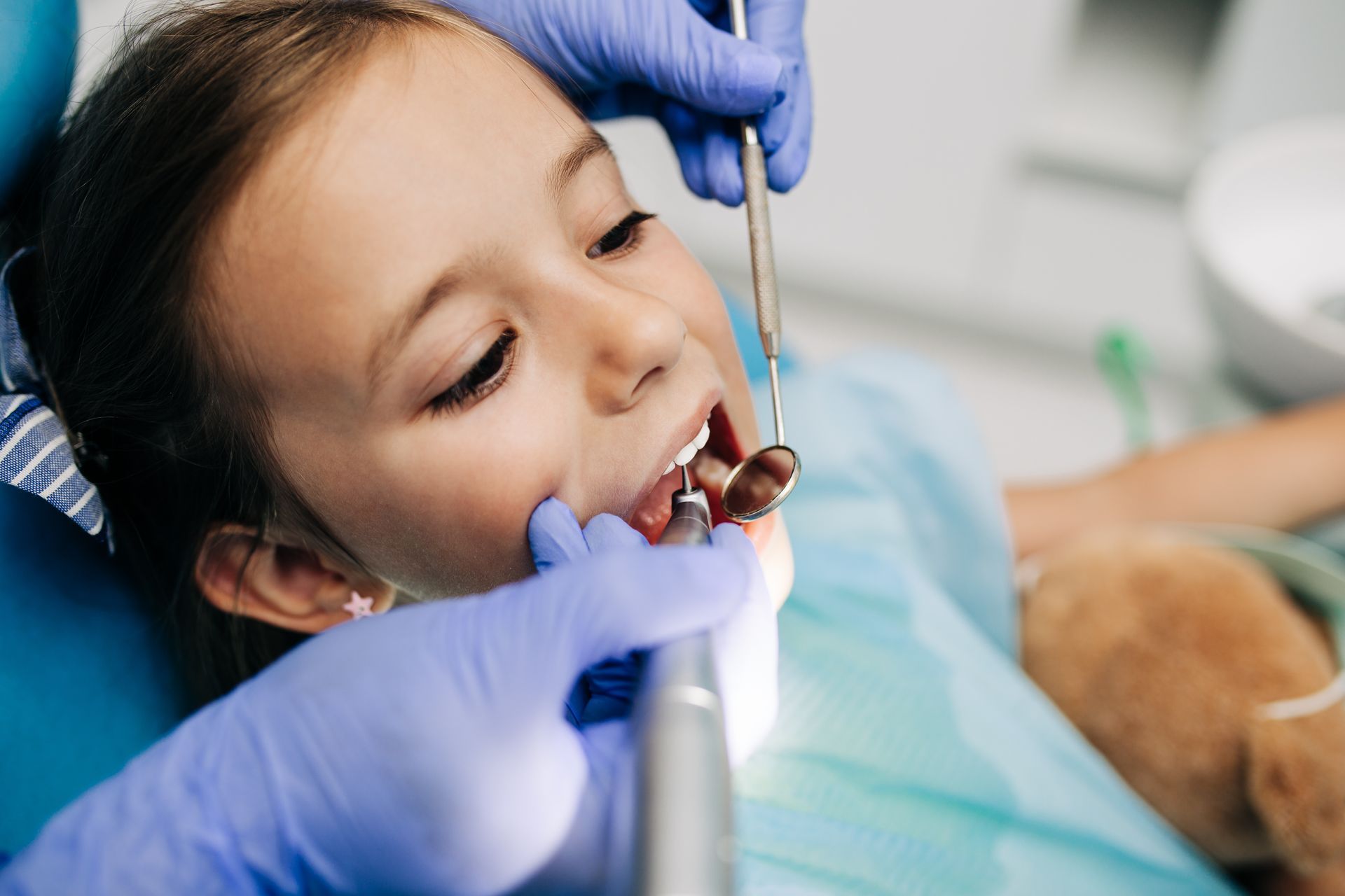 A little girl is getting her teeth examined by a dentist.