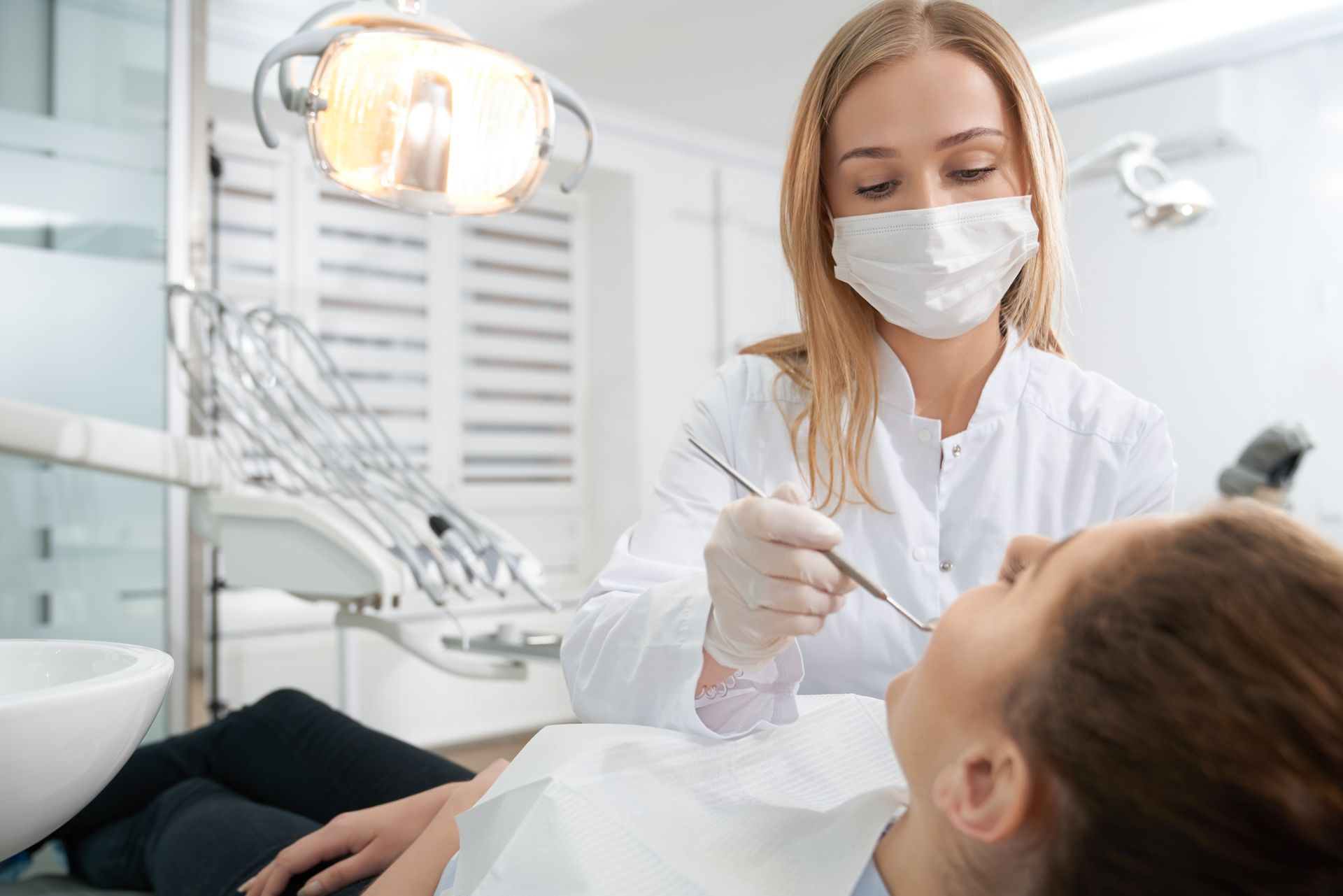 A female dentist is examining a woman 's teeth in a dental office.