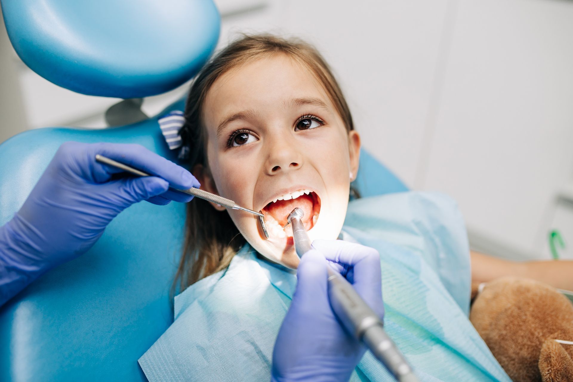 A little girl is getting her teeth examined by a dentist.