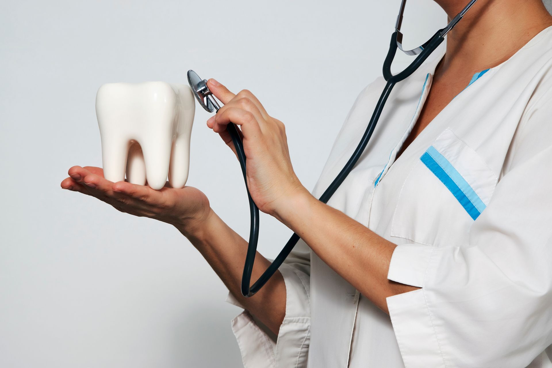 A dentist is examining a tooth with a stethoscope.