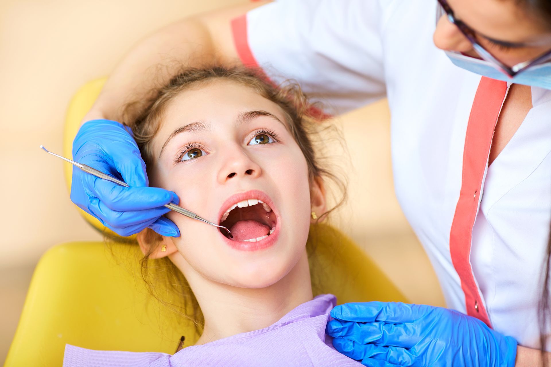 A young girl is having her teeth examined by a dentist.