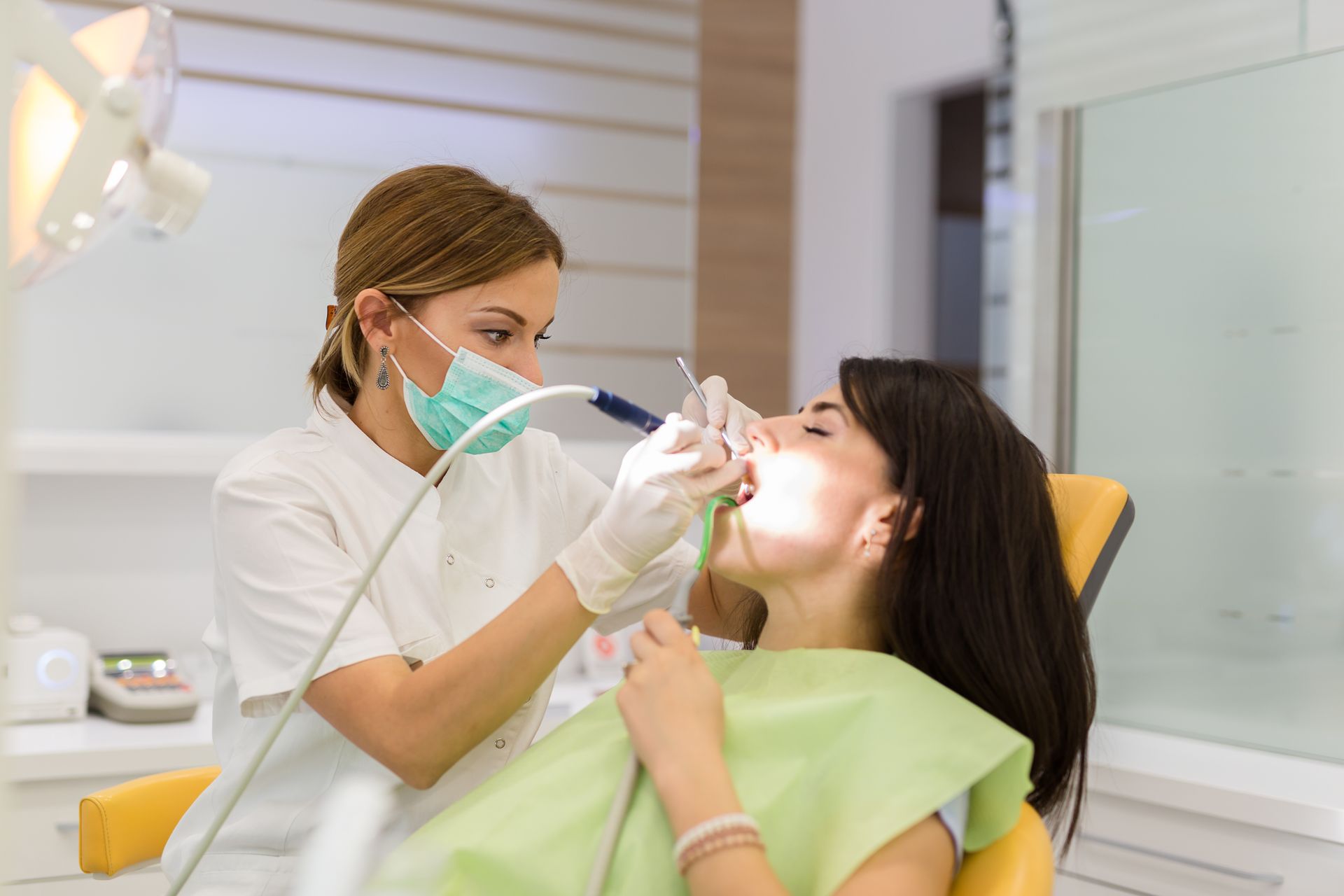 A woman is getting her teeth examined by a dentist in a dental office.