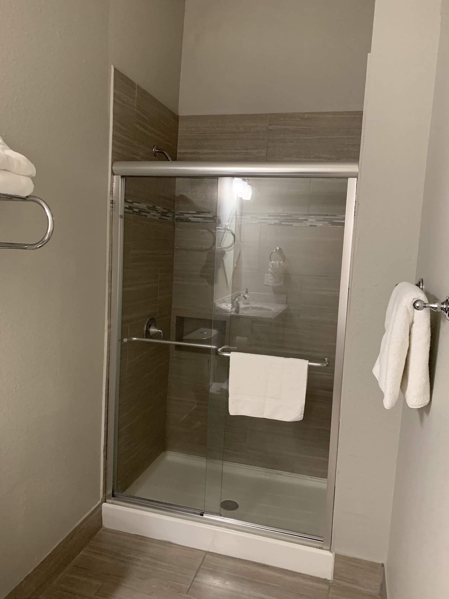 A bathroom with a sliding glass shower door and towels hanging on the wall.