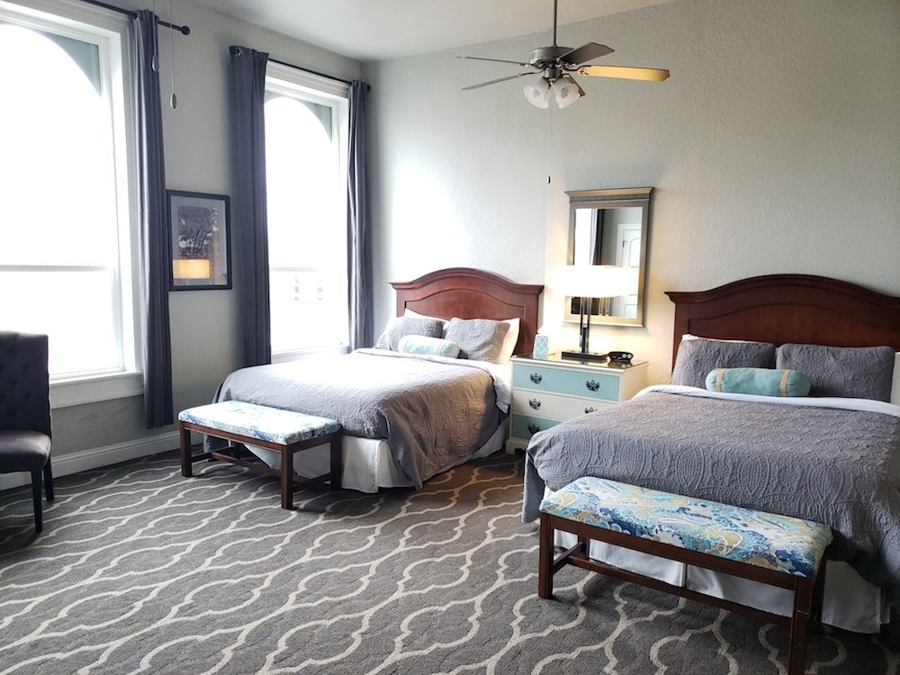 A hotel room with two beds and a ceiling fan.