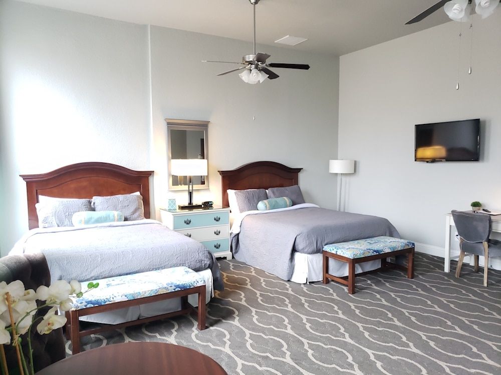 A hotel room with two beds , a desk and a television.