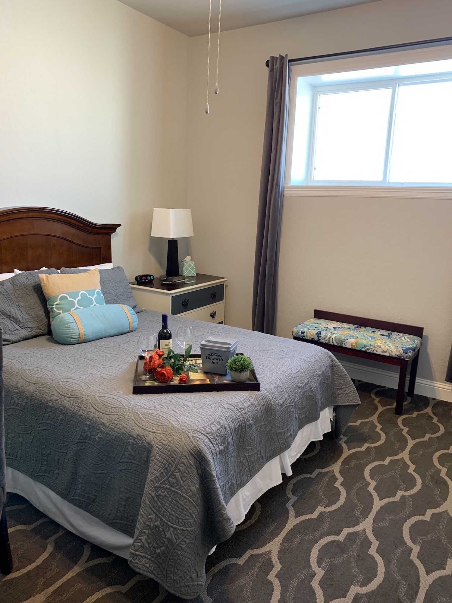 A bedroom with a bed and a window with a tray on the bed.