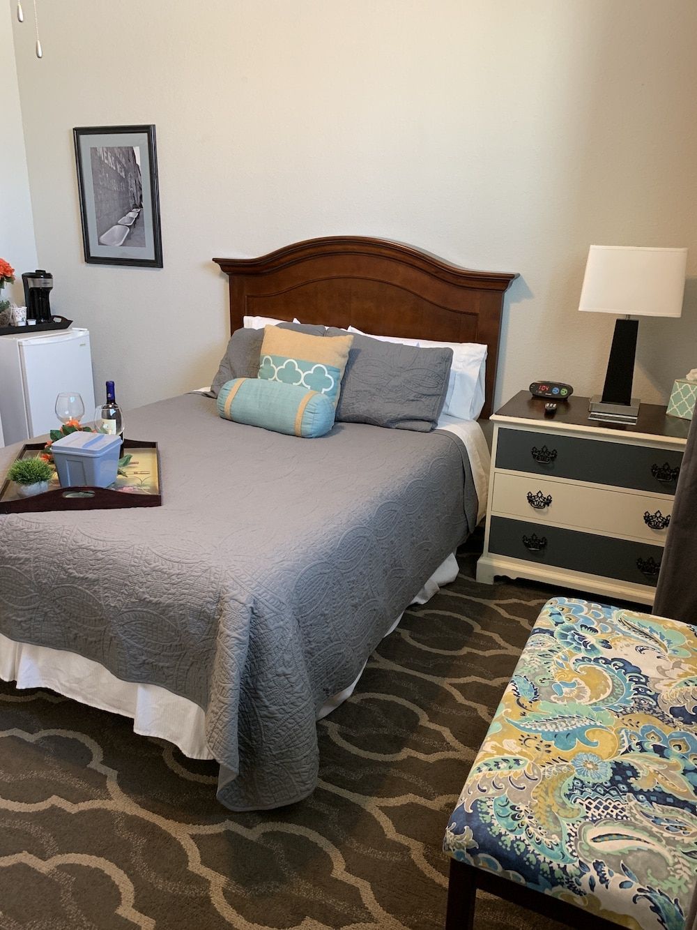 A bedroom with a bed , dresser , chair and lamp.