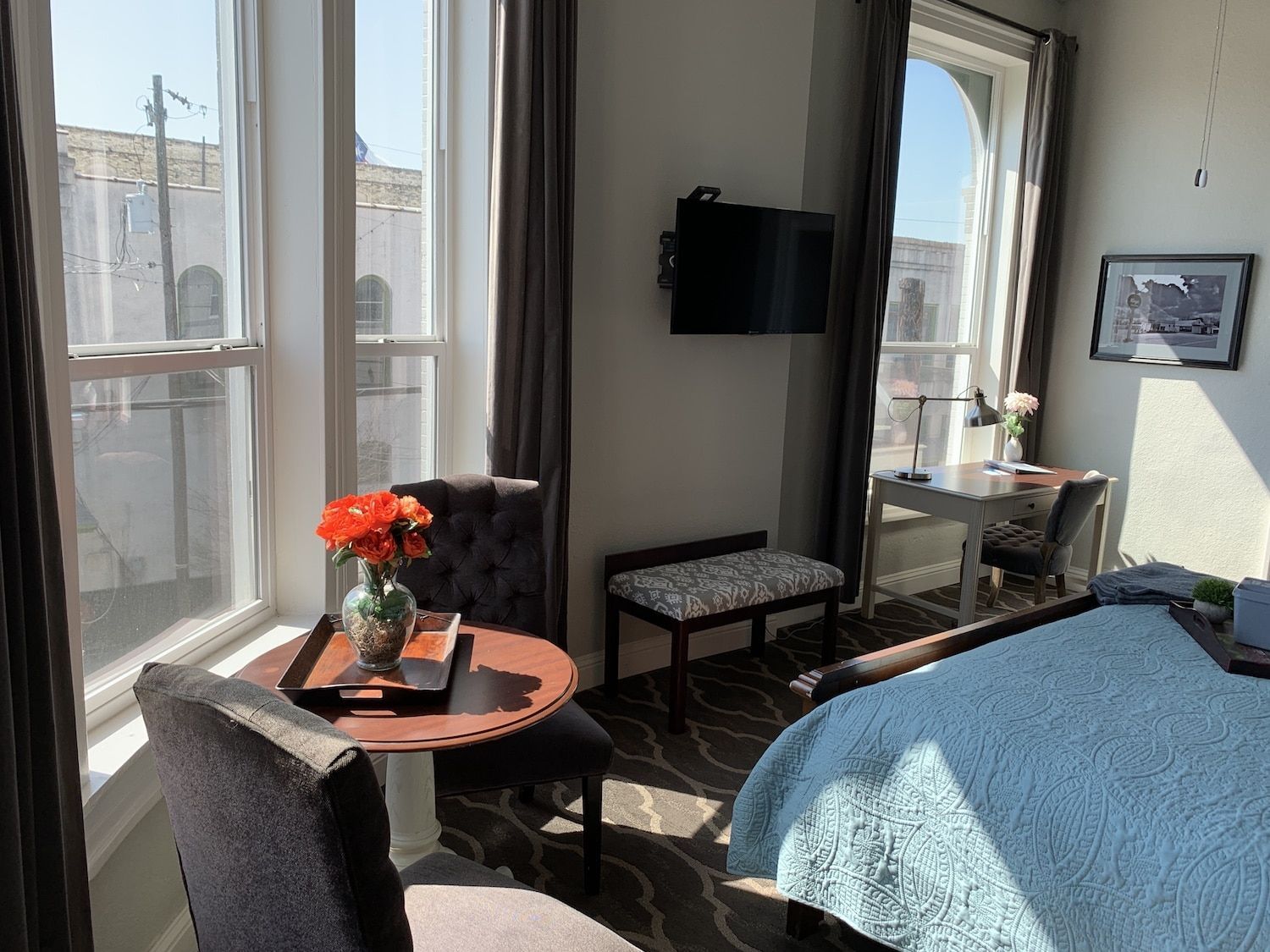 A hotel room with a bed , chairs , table and television.