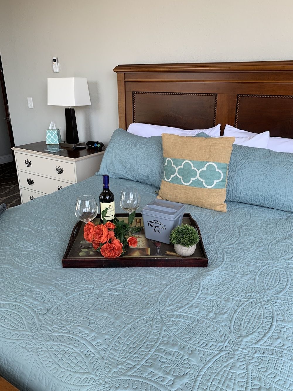 A bed with a tray of flowers and wine on it.