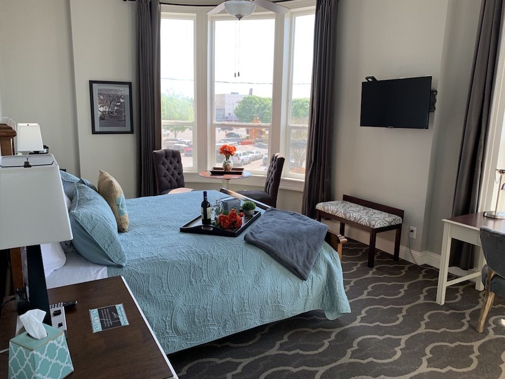 A bedroom with a king size bed , desk , chairs and a flat screen tv.