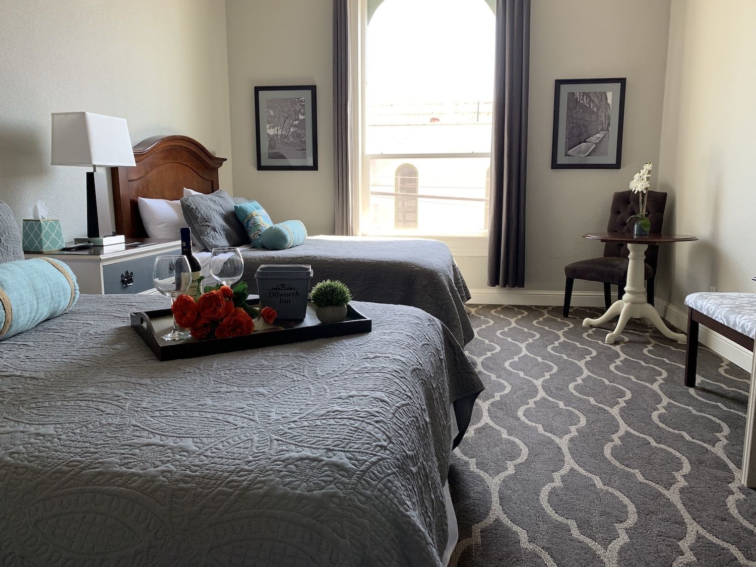 A bedroom with two beds , a table and a window.
