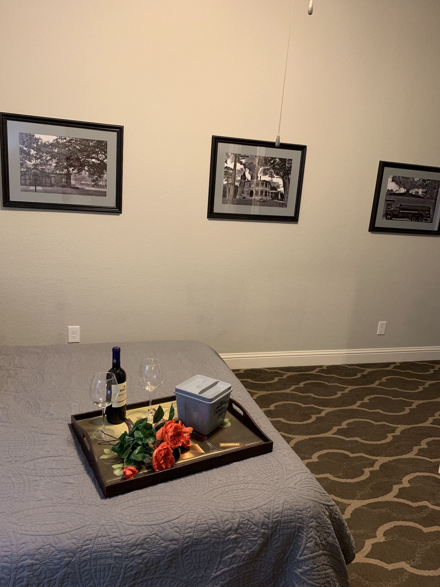 A bed with a tray of flowers and a bottle of wine on it