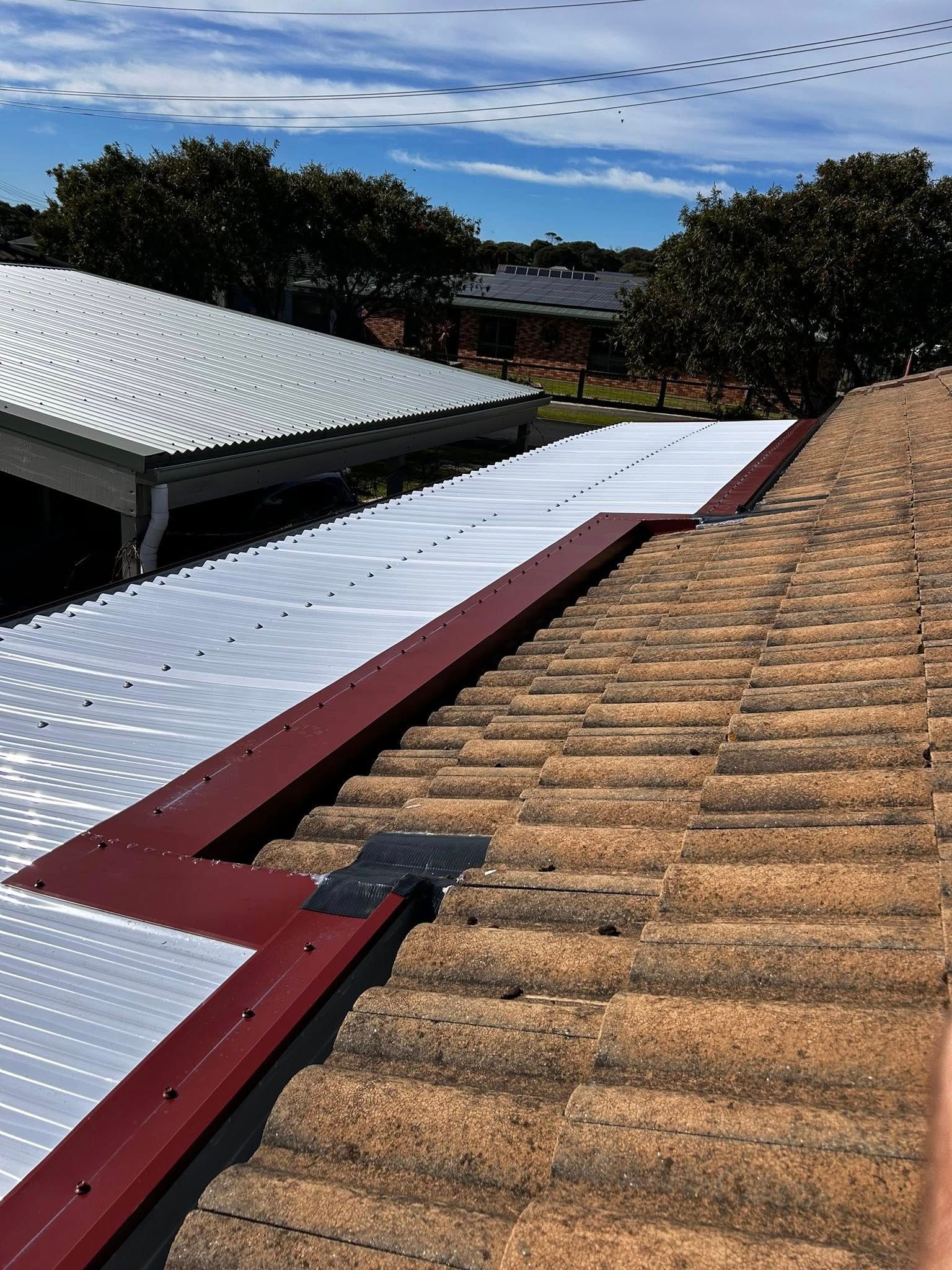 Weather vane on roof, a white house with a wooden deck and a blue sky.