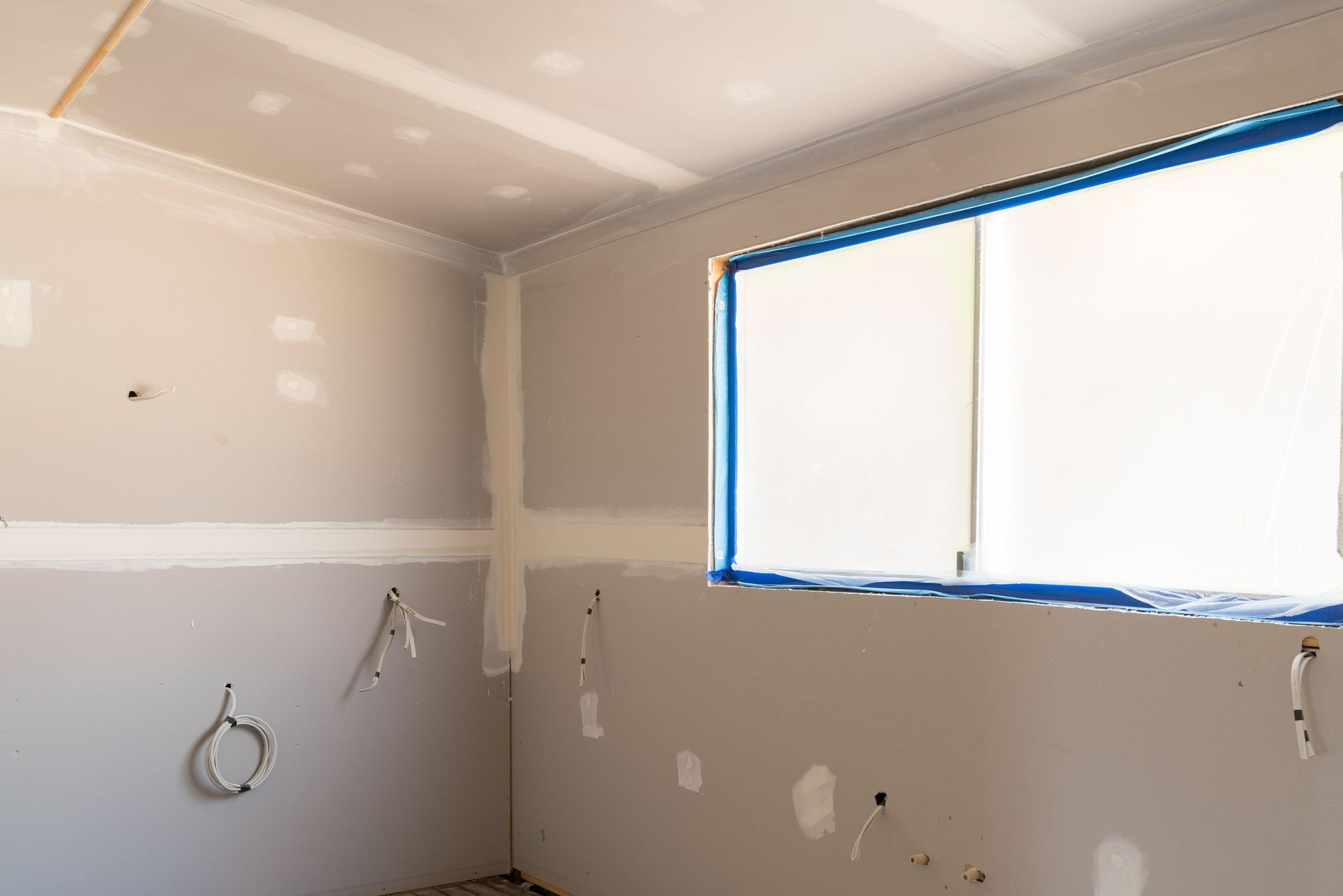 Interior room under construction with drywall and a window taped off.