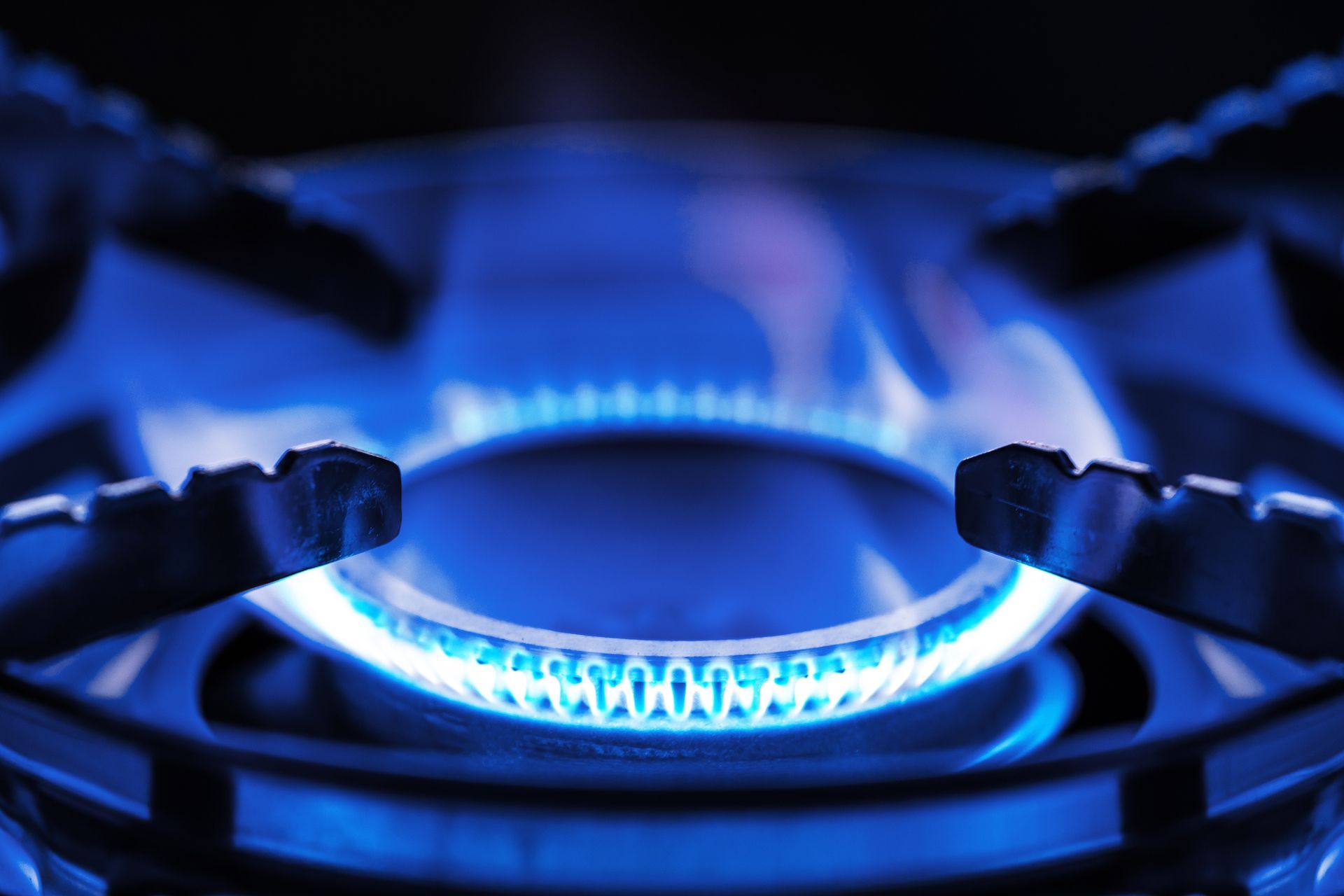 Pool filter system with gray pipes, valves, and tank, against a stucco wall, outdoors.