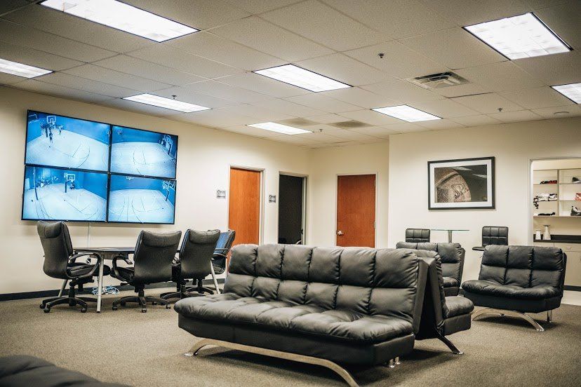 A monitoring room with a video wall, seating, and two closed doors. The room is lit by ceiling lights.