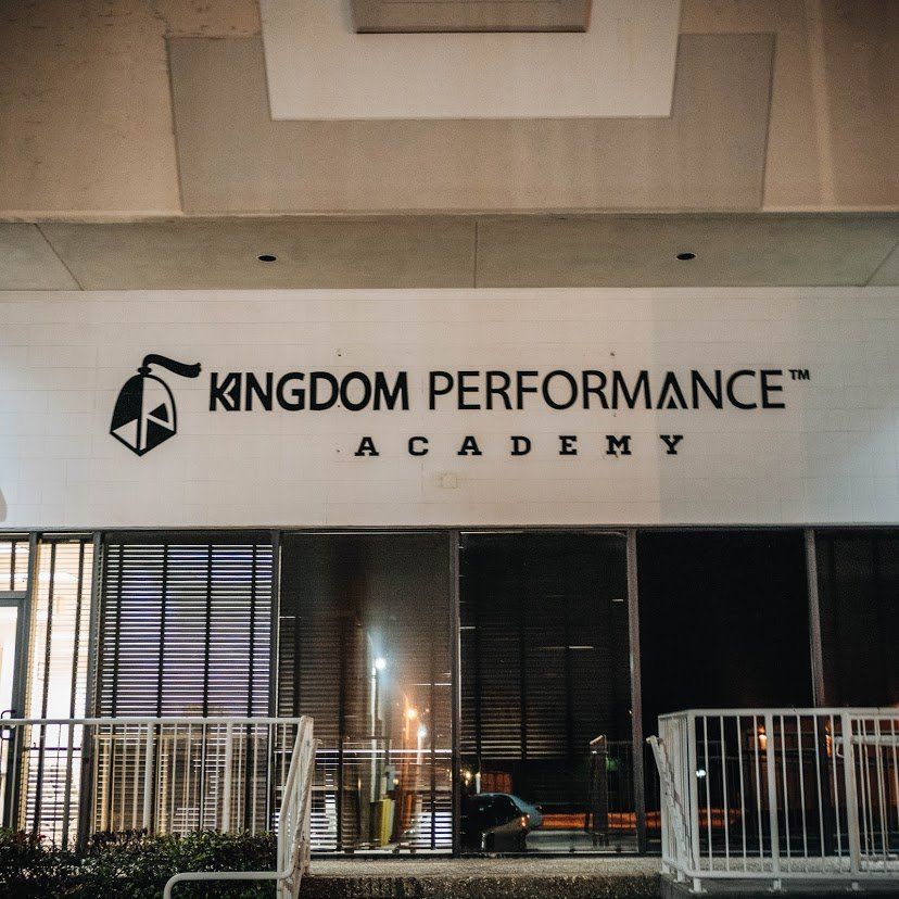 Kingdom Performance Academy sign on building exterior at night.