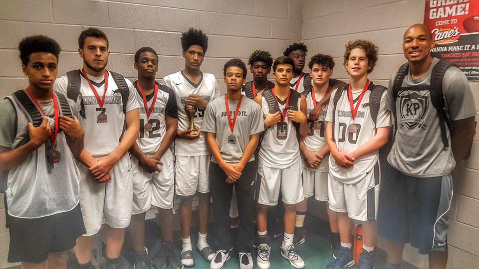 Basketball team poses with medals and trophy after winning a game. Players and coach are inside.