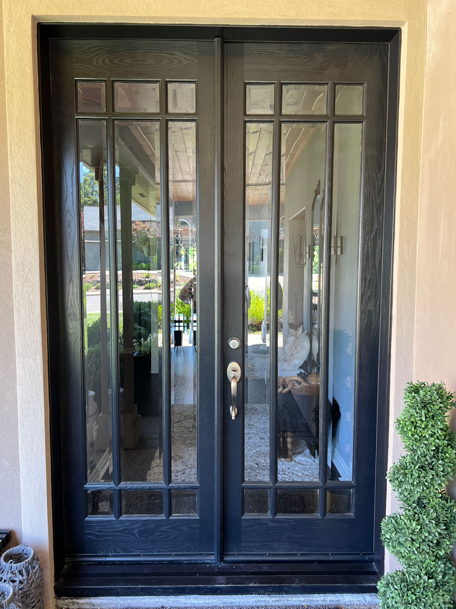 Black double doors with glass panes, set in a light-colored stone or stucco entryway.
