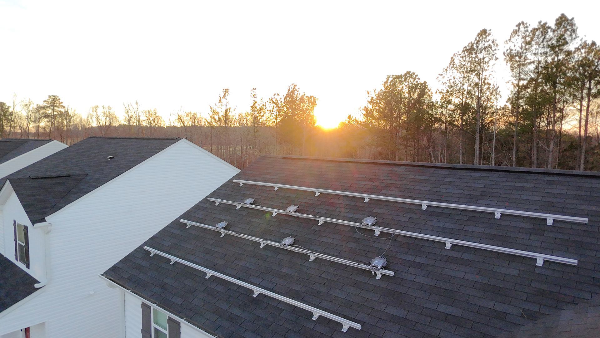 An aerial view of a house with solar panels installed on its dark shingled roof.