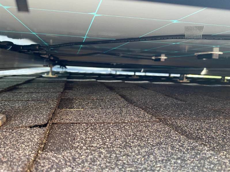 Solar panels installed above a dark shingle roof with visible support brackets.
