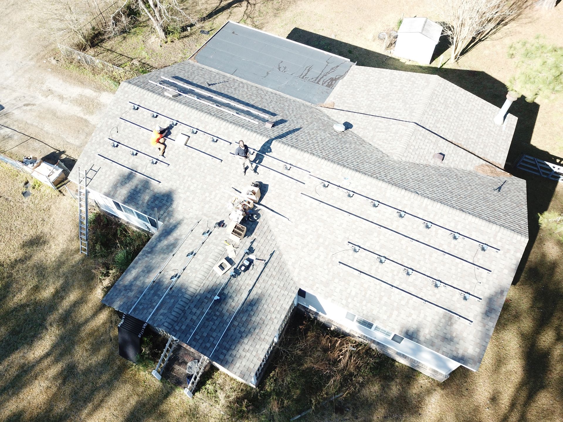 Aerial view of workers installing solar panels on a house roof.