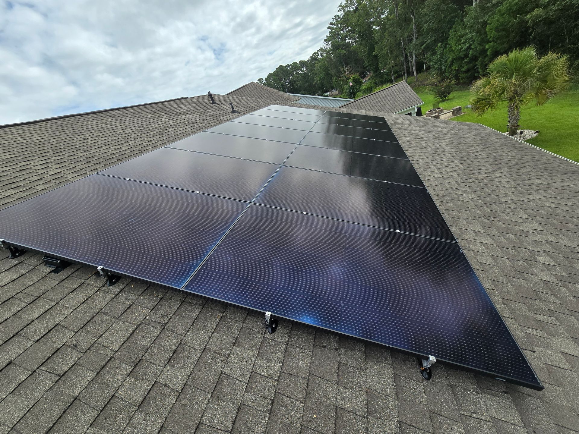 Solar panels installed on a residential roof under a cloudy sky.