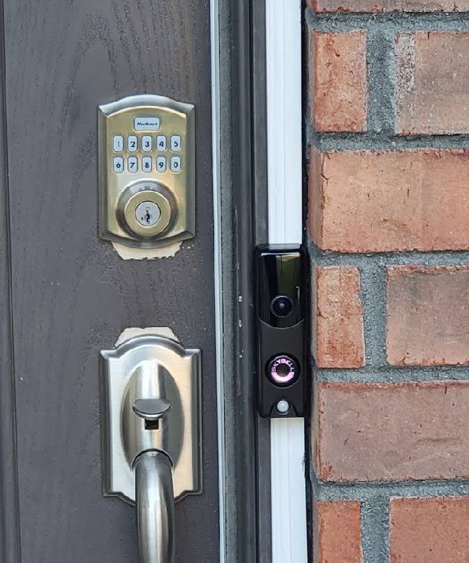 Door with keypad lock and doorbell camera on brick wall.