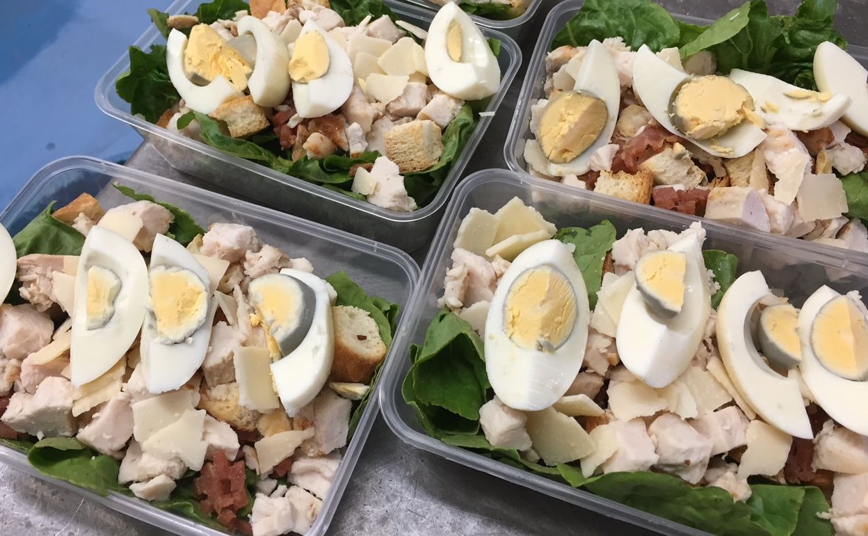 Pre-packaged salads with hard-boiled eggs, chicken, croutons, and lettuce in clear containers— Bread Basket in Kurri Kurri, NSW