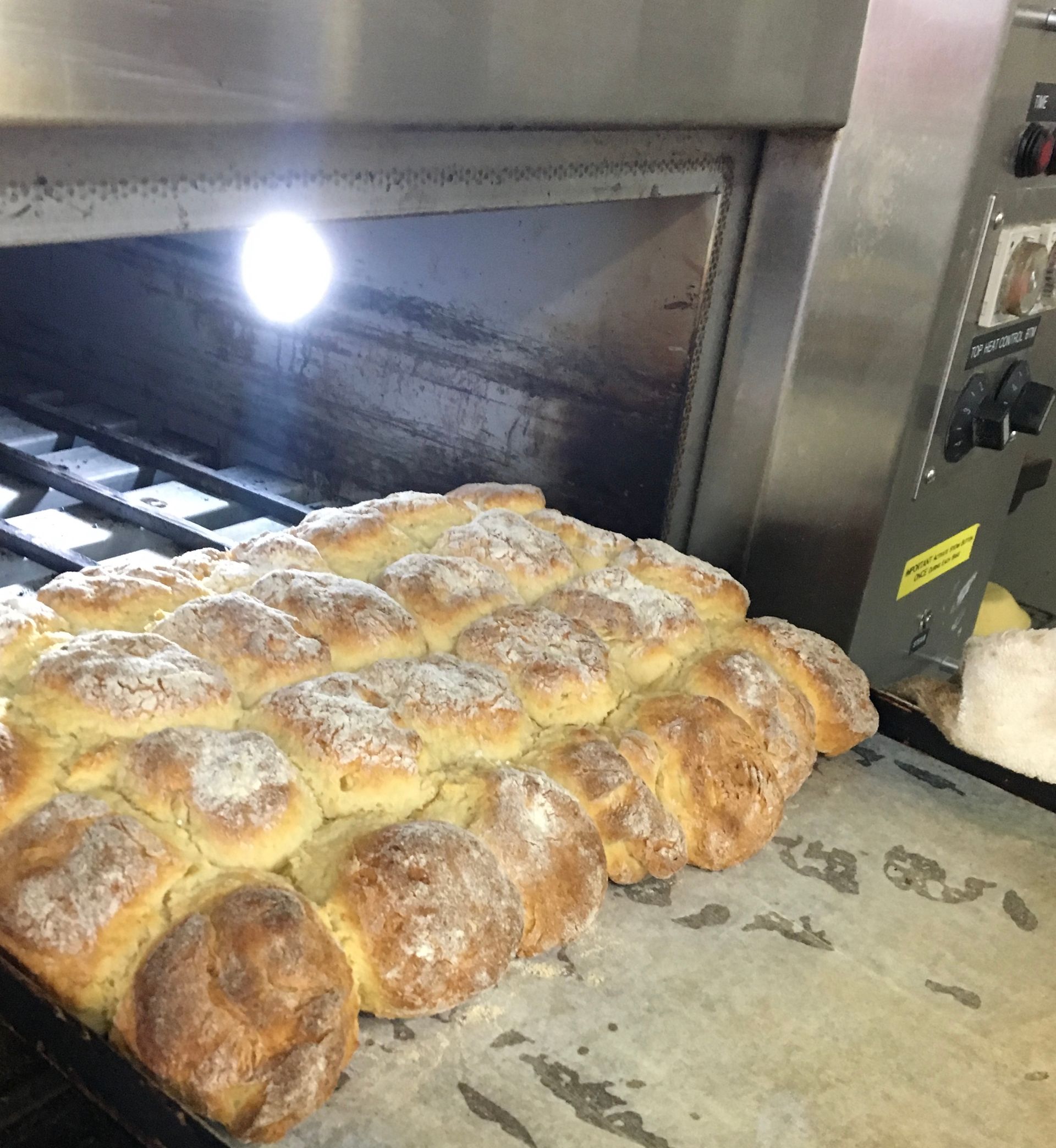 A tray of baked bread rolls inside an oven with a bright light, ready for removal— Bread Basket in Kurri Kurri, NSW