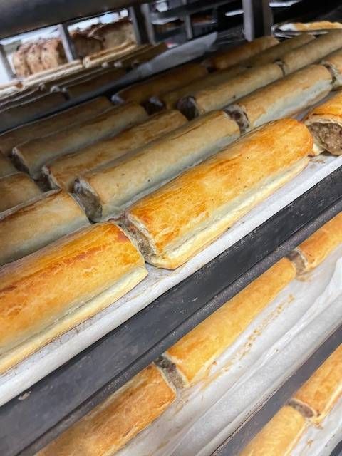 Rows of golden-brown sausage rolls on a bakery display shelf— Bread Basket in Kurri Kurri, NSW