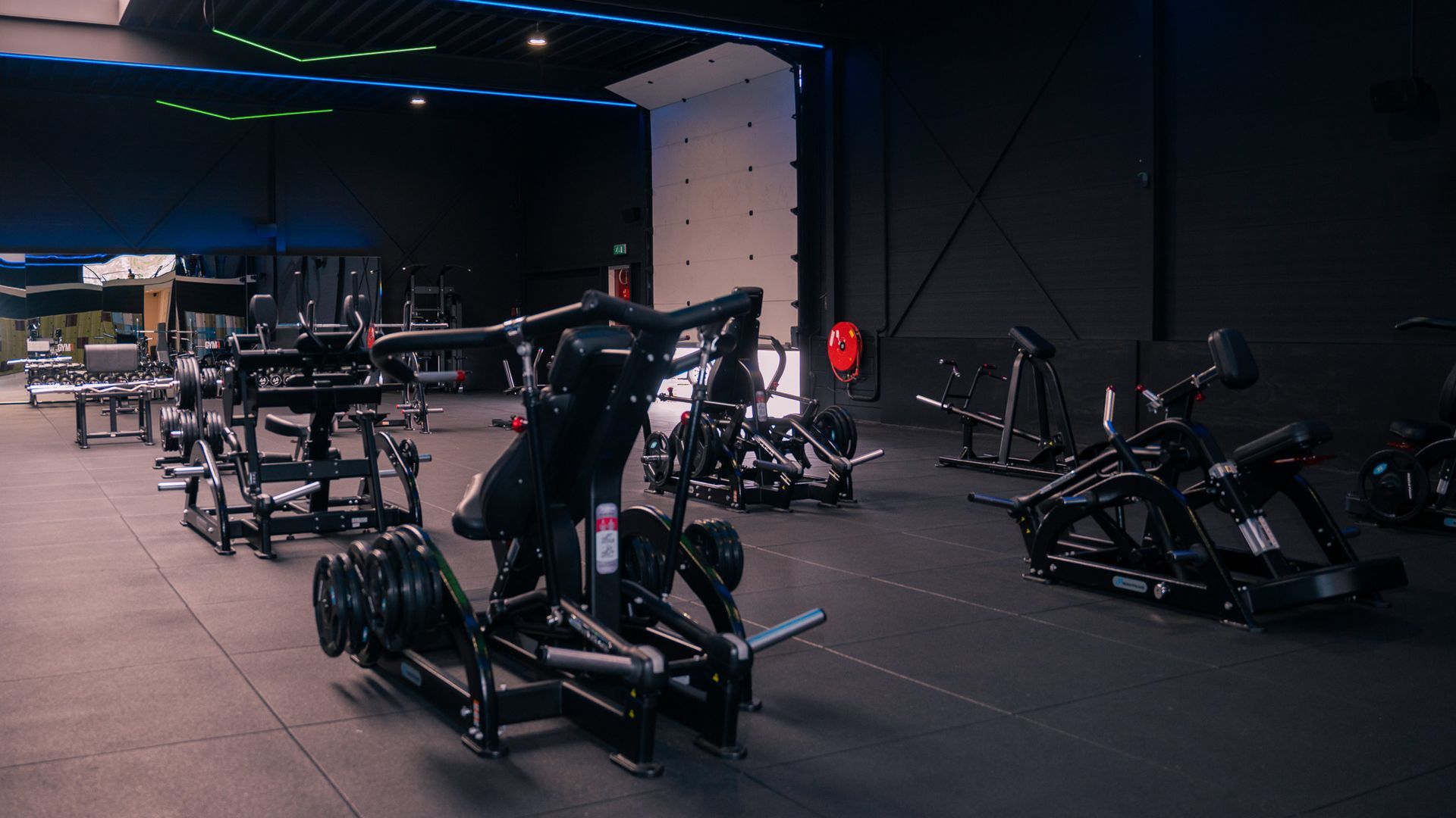 een man hurkt om een ​​halter op te tillen in een sportschool.