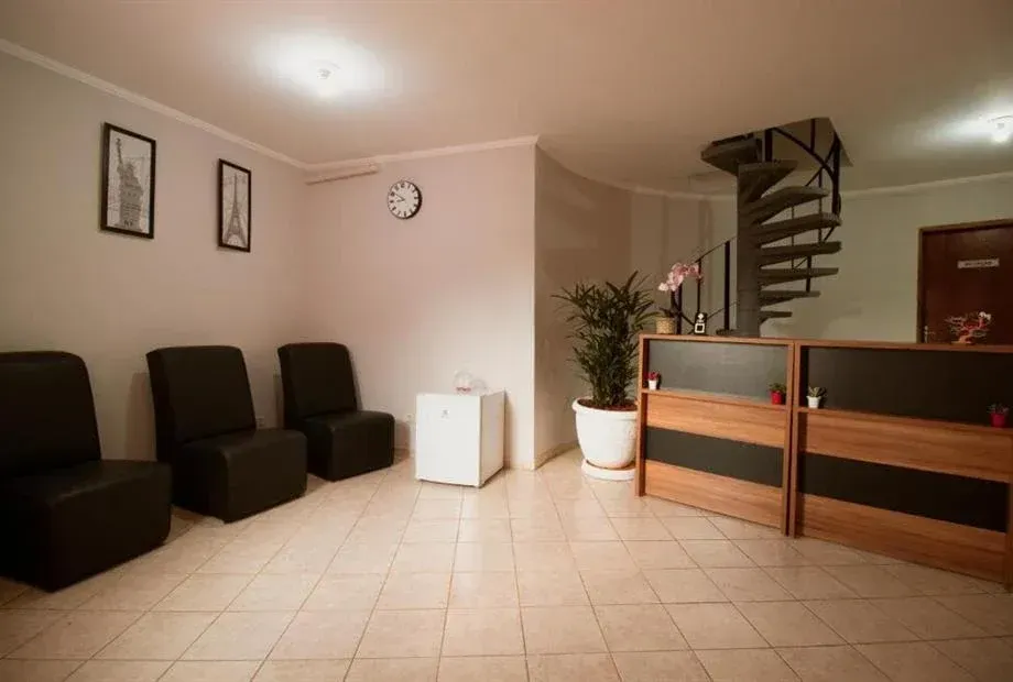 Área de recepção com cadeiras pretas, escada em espiral e balcão de atendimento.