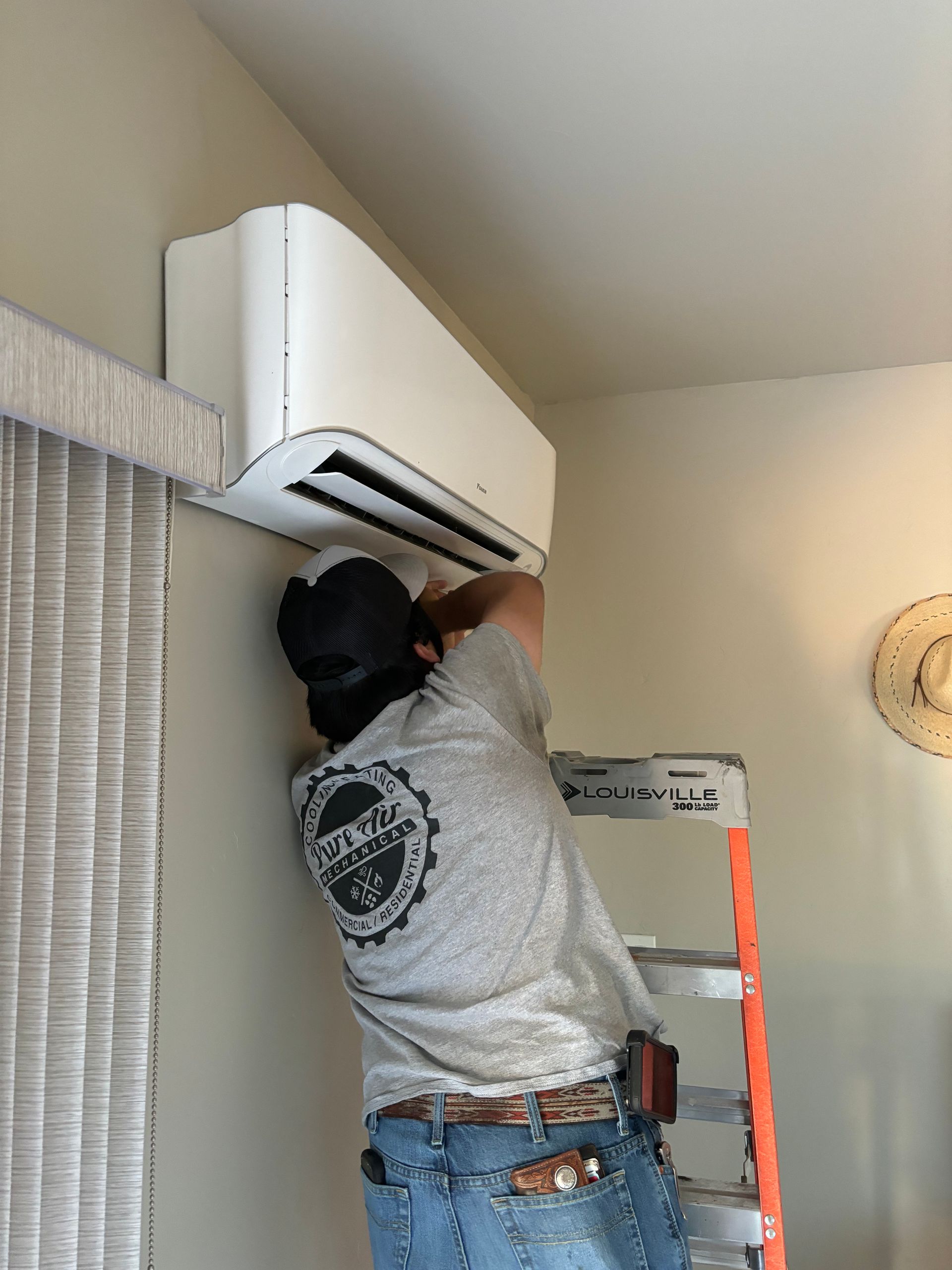 A man is installing an air conditioner on a wall.