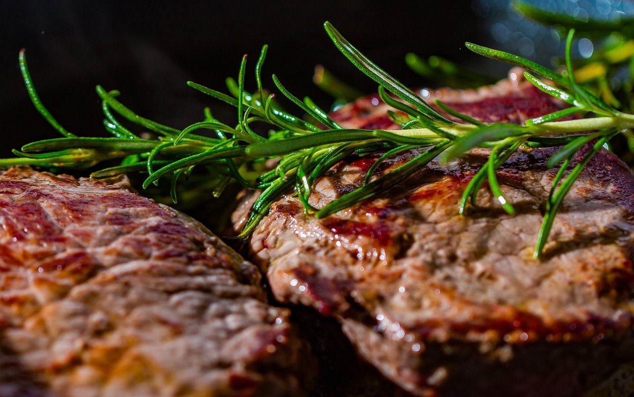 a close up of a steak with rosemary on top .